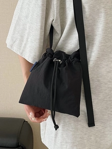 Minimalist black nylon drawstring bucket bag with adjustable shoulder strap for casual travel