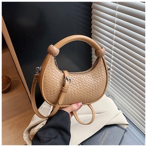 Detailed close-up of woven dumpling bag with spherical knot handle and metal hardware