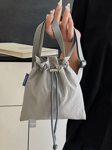Light grey nylon drawstring bucket bag with adjustable straps and brand woven label