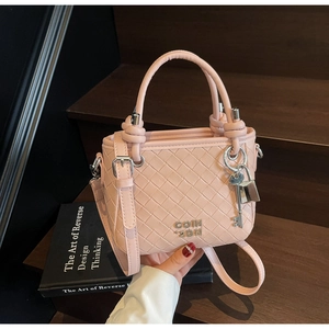 Detailed close-up of pink woven bucket bag with metallic logo and decorative key pendant