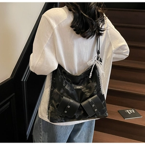 Detail view of black patent leather tote featuring vintage texture and lace pearl bow