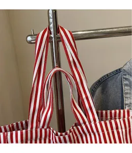 Detailed close-up of durable reinforced wide straps on a red and white striped canvas tote