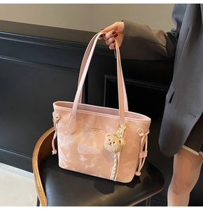 Detail of pink marble pattern tote bag featuring a plush bear charm and long handles