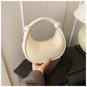 Detail of off-white dumpling bag with faux crocodile pattern and large bead handles