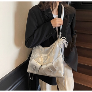 Detail showing metallic silver tote bag with decorative pockets and pearl lace bow charm