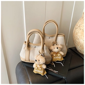 Detail of canvas bucket bags with faux leather trim and cute teddy bear charm accessory