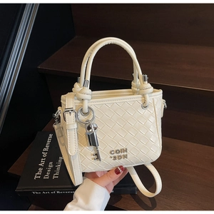 Close-up of cream woven leather bucket bag with metallic branding and lock pendant