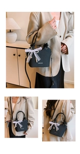 Détail du sac seau noir avec nœud en dentelle, breloque perle et bandoulière amovible