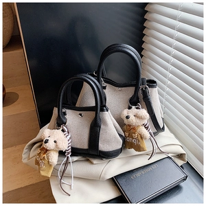 Detail of canvas bucket bags with black leather trim and cute brown plush bear pendant