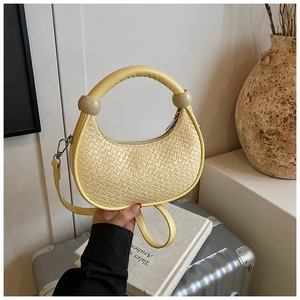 Detail of light yellow woven leather dumpling bag with ring handle and crossbody strap