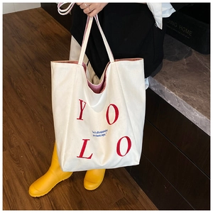 Detail of canvas tote bag showing YOLO print and red striped inner lining texture
