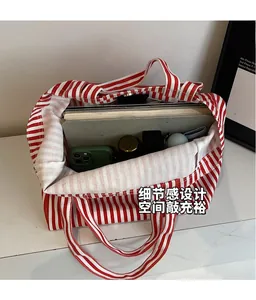 Detail view of red and white striped canvas tote bag showing spacious interior with books