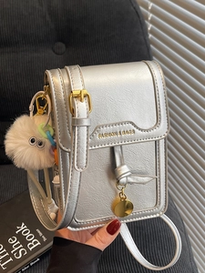 Silver metallic mini crossbody phone bag with pleated texture and fuzzy monster charm