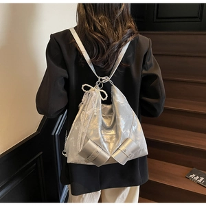 Detail of silver hobo bag featuring pearl bow and lace ribbons on smooth satin surface
