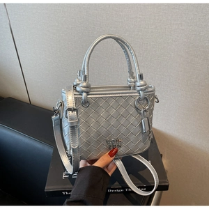 Close-up of silver woven bucket bag with metal logo and lock charm detail