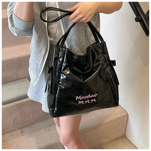 Detail of black patent leather tote bag with pink butterfly and Mooduo embroidery