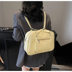 Detail of a creamy yellow PU leather backpack featuring an embossed logo and outer pocket