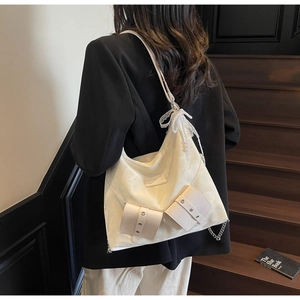 Detail of cream white nylon tote bag with elegant lace bow and pearl pendant decoration