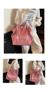 Detail view of the large capacity canvas tote bag with red stripes and Monday print