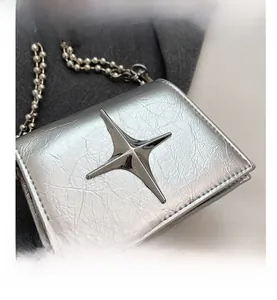 Detail of silver metallic mini bag with star ornament and sleek ball chain strap