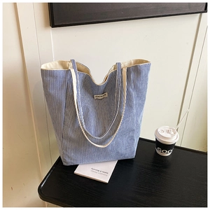 Detail of blue striped canvas tote bag with woven label and spacious inner lining