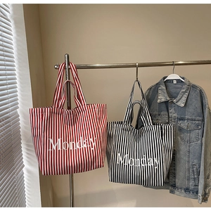 Close-up of red and black striped canvas tote bags with Monday lettering on hangers