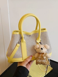 Stylish beige canvas and yellow leather bucket bag with cute bear pendant and shoulder strap