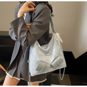 Close-up of light blue marble-pattern tote bag with a bow and elegant pearl chain