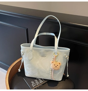 Detail of blue marble pattern tote bag with brown plush bear charm and sturdy handles