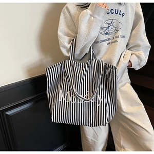 Detail of large canvas tote bag with black and white vertical stripes and Monday text