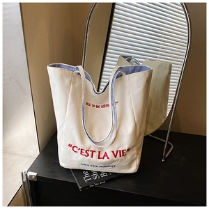 Detailed view of the striped inner lining and red C'EST LA VIE embroidery on the tote