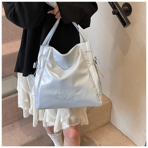Detail of light blue glossy tote bag with metallic texture and ribbon drawstring