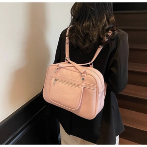 Pink PU leather JK uniform bag with embossed logo worn over a black blazer