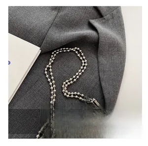 Close-up of silver leather mini bag with beaded metal chain and star ornament detail