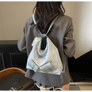 Detail of light blue bow backpack with metal chain strap and white lace pearl charm