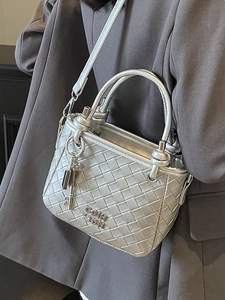 Silver woven metallic leather bucket bag with top handle and detachable strap on model