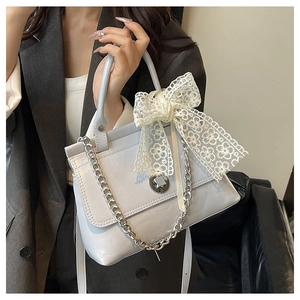 Détail du sac bleu clair brillant avec grand nœud en dentelle blanche et chaîne argent