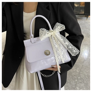 Détail du sac à main en cuir lilas avec nœud en dentelle et fermoir rotatif en métal