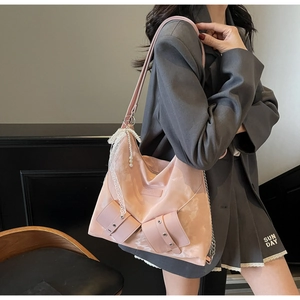Detail of peach pink tote bag featuring lace trim, pearl pendant, and metal buckle accents