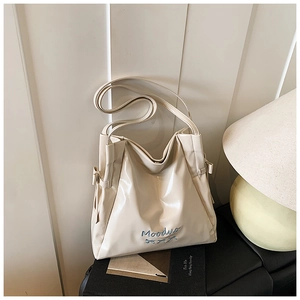 Detailed view of cream hobo bag featuring blue Mooduo embroidery and glossy leather finish