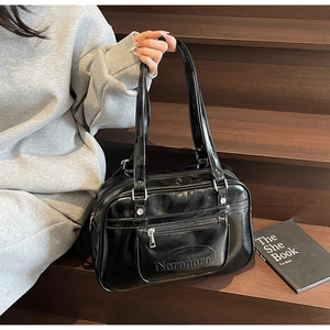 Detail of glossy black leather tote bag with front zipper pocket and embossed logo
