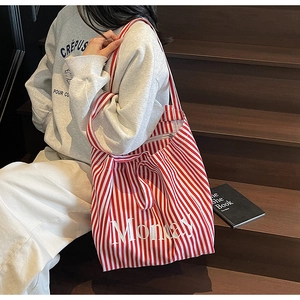 Detail of red striped canvas tote bag with Monday text print in a casual lifestyle setting