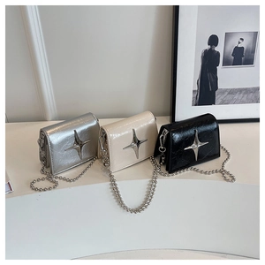 Close-up of three pleated patent leather mini bags with silver star charms and bead chains