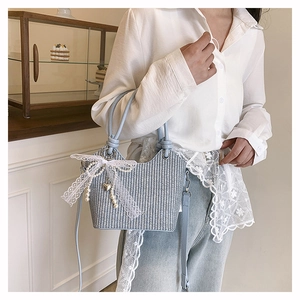 Détail du sac seau tissé bleu clair avec nœud en dentelle blanche et perles chic