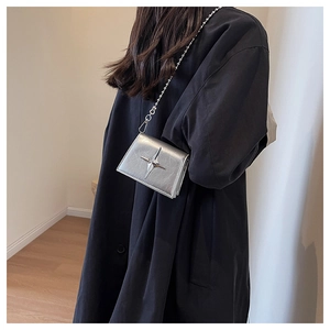 Chic silver mini crossbody bag with star clasp worn on a black coat for Y2K styling