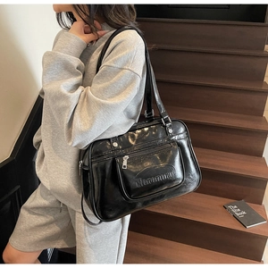 Detail of black glossy faux leather shoulder bag with a functional front zipper pocket