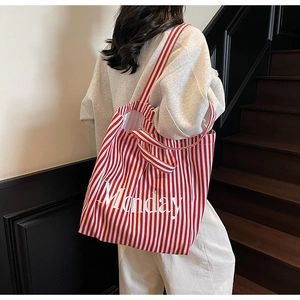 Detail of red and white striped canvas tote bag featuring Monday text on the front side