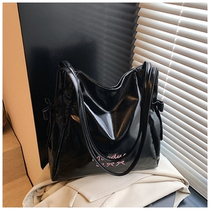 Detail of black glossy tote bag featuring pink Monday embroidery and side bow drawstrings