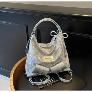 Close-up of silver tote bag featuring pearl lace bow and decorative double bow buckles
