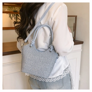 Détail du sac seau tissé bleu et blanc avec poignée nouée et finition texturée maille